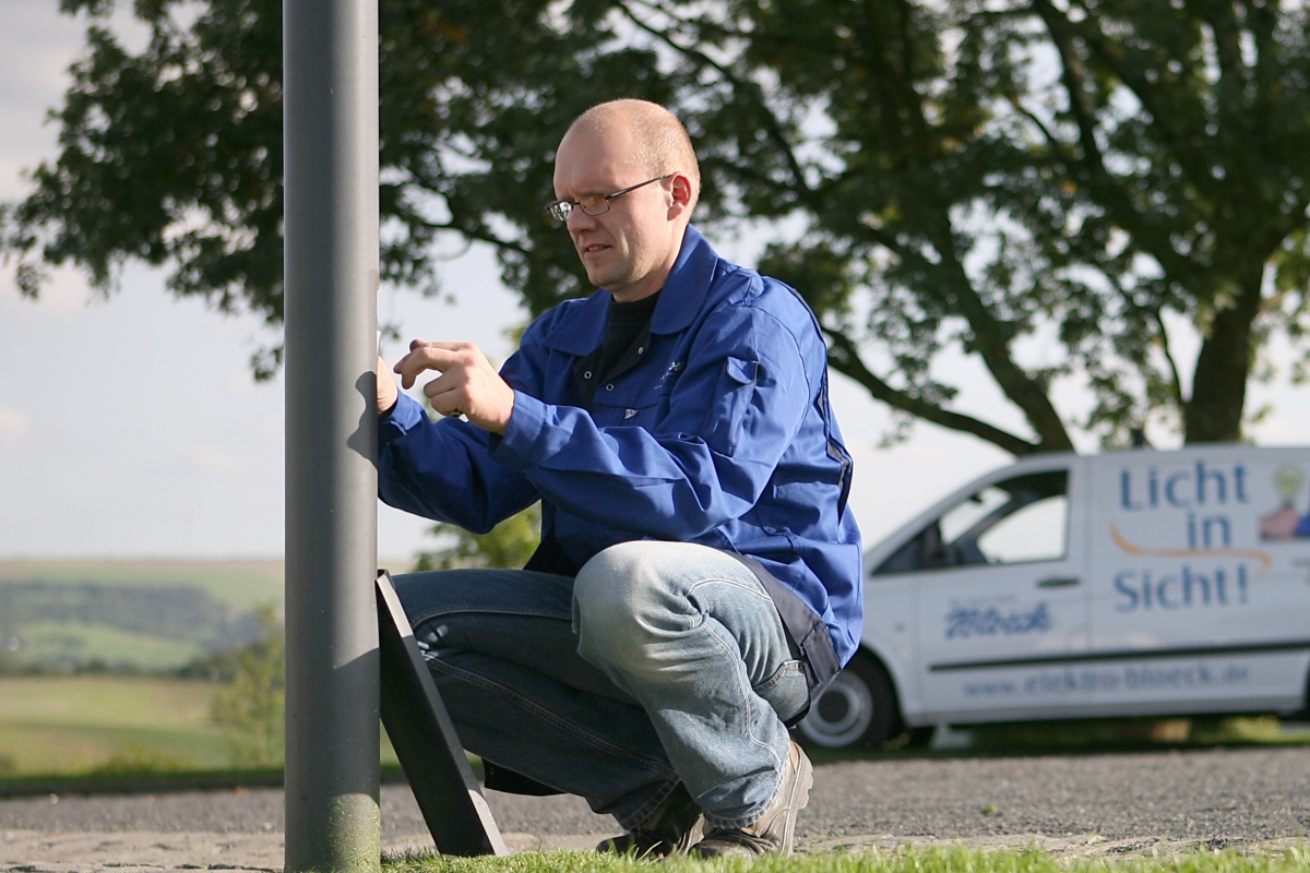 Mitarbeiter von Elektro Bloeck Trier bei Arbeiten an einem Lampenmast im Außenbereich
